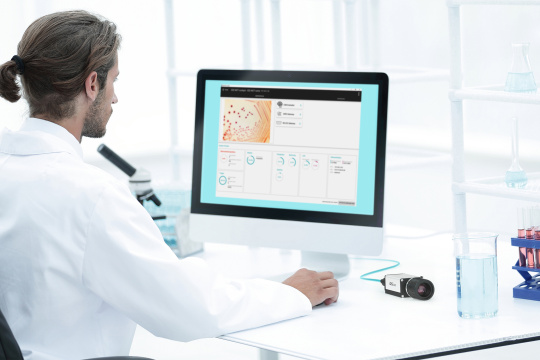 Ein Mann sitzt in einem Labor vor einem PC mit IDS lighthouse Software, nebenan befindet sich eine IDS NXT Kamera.