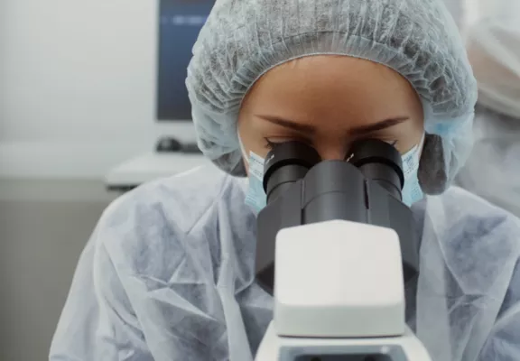 Eine Frau in einem Labor schaut in ein Mikroskop.