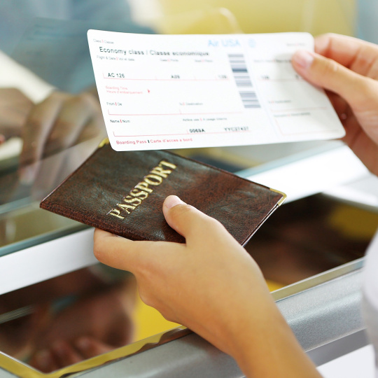 Eine Person hält ein Flugticket und einen Reisepass in der Hand.
