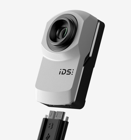 IDS Industriekamera uEye XC mit USB3-Kabel vor grauem Hintergrund.