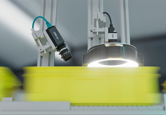 Industriekamera mit Objektiv und LED-Ringlicht inspiziert gelbes Fördergut