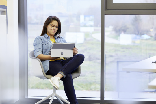 Eine IDS Mitarbeiterin, die im Büro sitzt mit ihrem Laptop auf dem Schoß. 