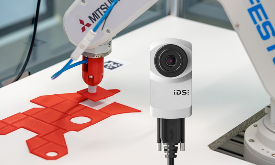 Roboterarm legt rotes Puzzleteil an exakt richtige Stelle, im Vordergrund uEye XC Kamera