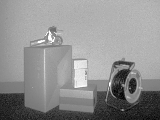 Graues Intensitätsbild der Nion 3D-Kamera zeigt verschiedene verschiedener Gegenstände vor einer Wand.