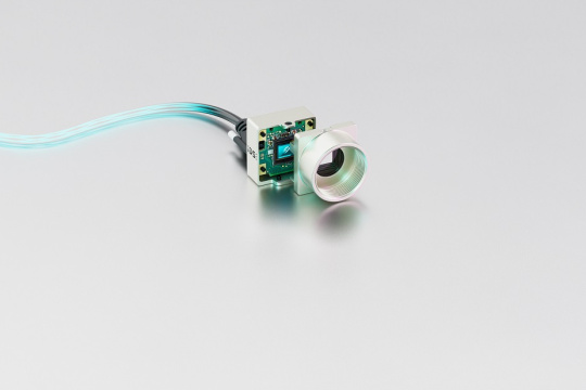 uEye XCP Kamera samt Kabel vor grauem Hintergrund.