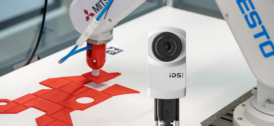Roboterarm legt rotes Puzzleteil an exakt richtige Stelle, im Vordergrund uEye XC Kamera