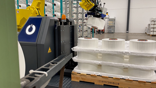 Roboterarm sortiert Papierrollen auf einer Palette