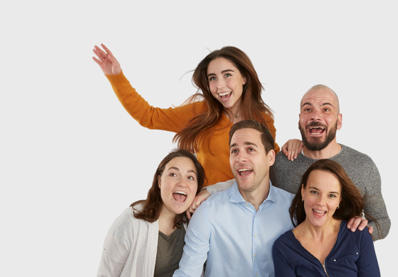 Fünf IDS Mitarbeiter stehen lachend als Gruppe zusammen vor einem weißen Hintergrund.