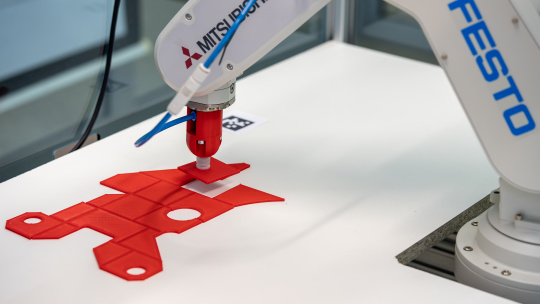 Roboterarm platziert Bauteil an vorgegebener Position.