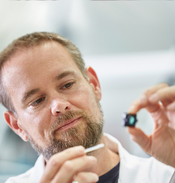 Bild von einem IDS Mitarbeiter, der einen Sensor von einer Platine reinigt.