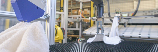 Gelbe Robotergreifarme mit Handtüchern in Wäscherei mit IDS Industriekameras.